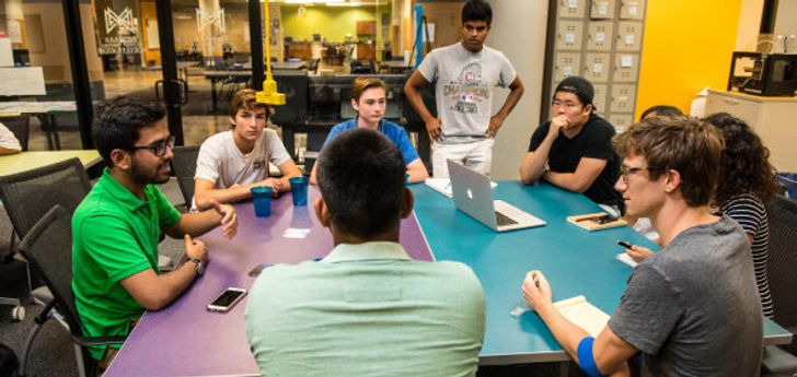 A group of students sit around a table in a brightly colored space