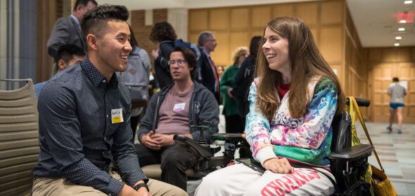 Two people sitting and talking together. One is seated in a wheelchair.