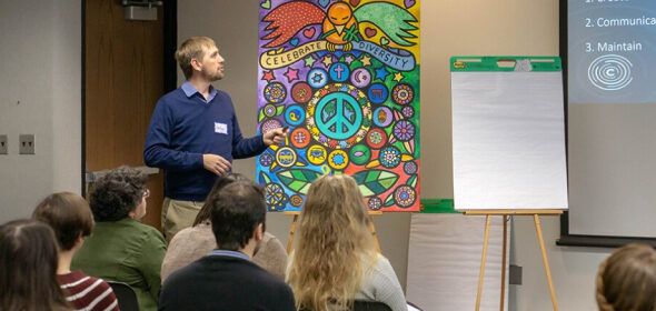 A person presenting with a colorful poster that says "Celebrate Diversity"