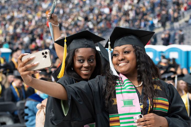 Black sorority sisters wearing caps and gowns and sashes representing their sorority