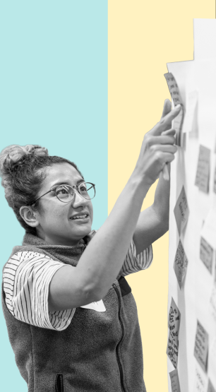 A person putting a sticky note on a wall with other notes