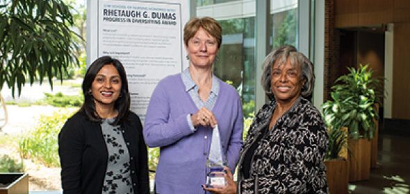 Three people standing together holding a glass award