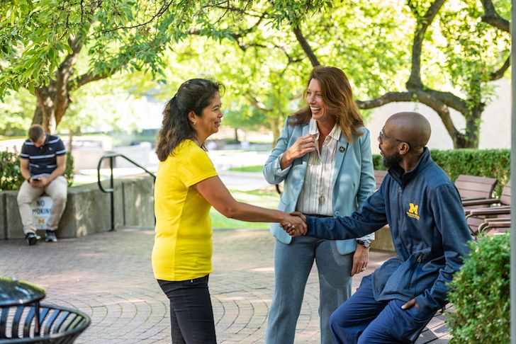 Michigan Medicine staff members shaking hands and talking outdoors